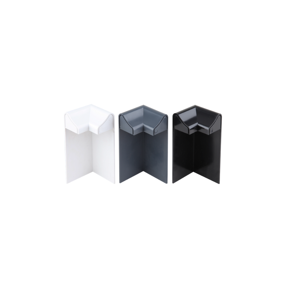 A white, an anthracite grey, and a black external edge trim corner, standing upright to emphasise their shape and colour.